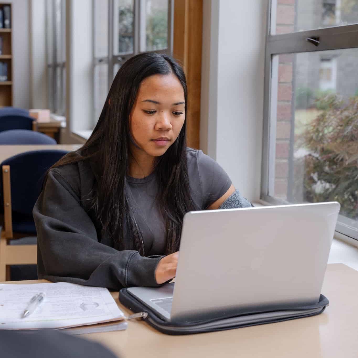 Male student smiles while typing on computer