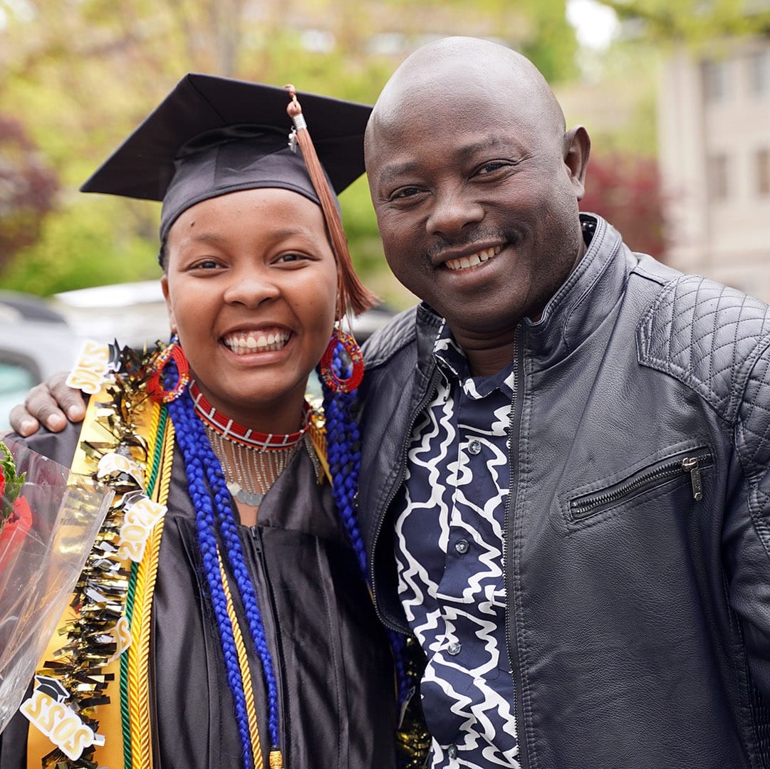 Female student in gown on commencement with family member