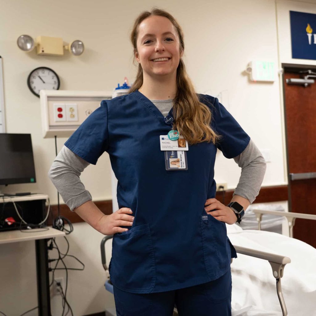 Female nursing student smiles while in simulation lab