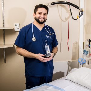 Male nurse checks equipment in clinic room while smiling