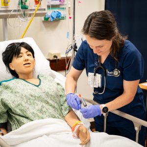 Female nursing student practices in simulation lab with full mannequin