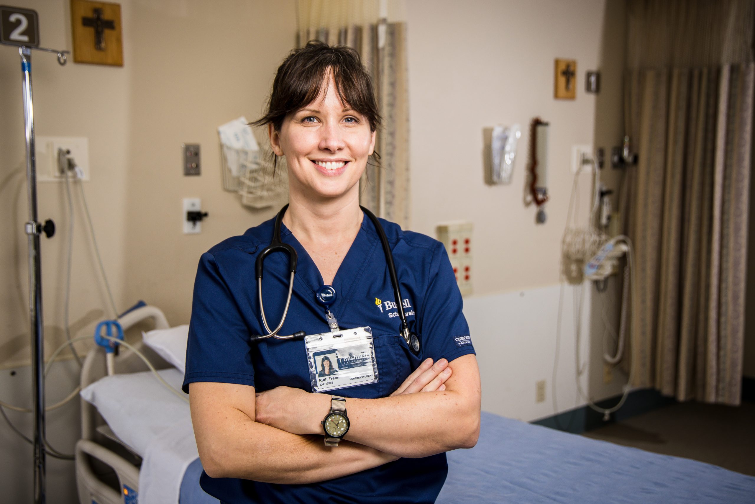 Confident nursing student in blue scrubs smiling in a clinic room