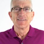 Headshot of a smiling man with short gray hair wearing glasses and a magenta polo shirt