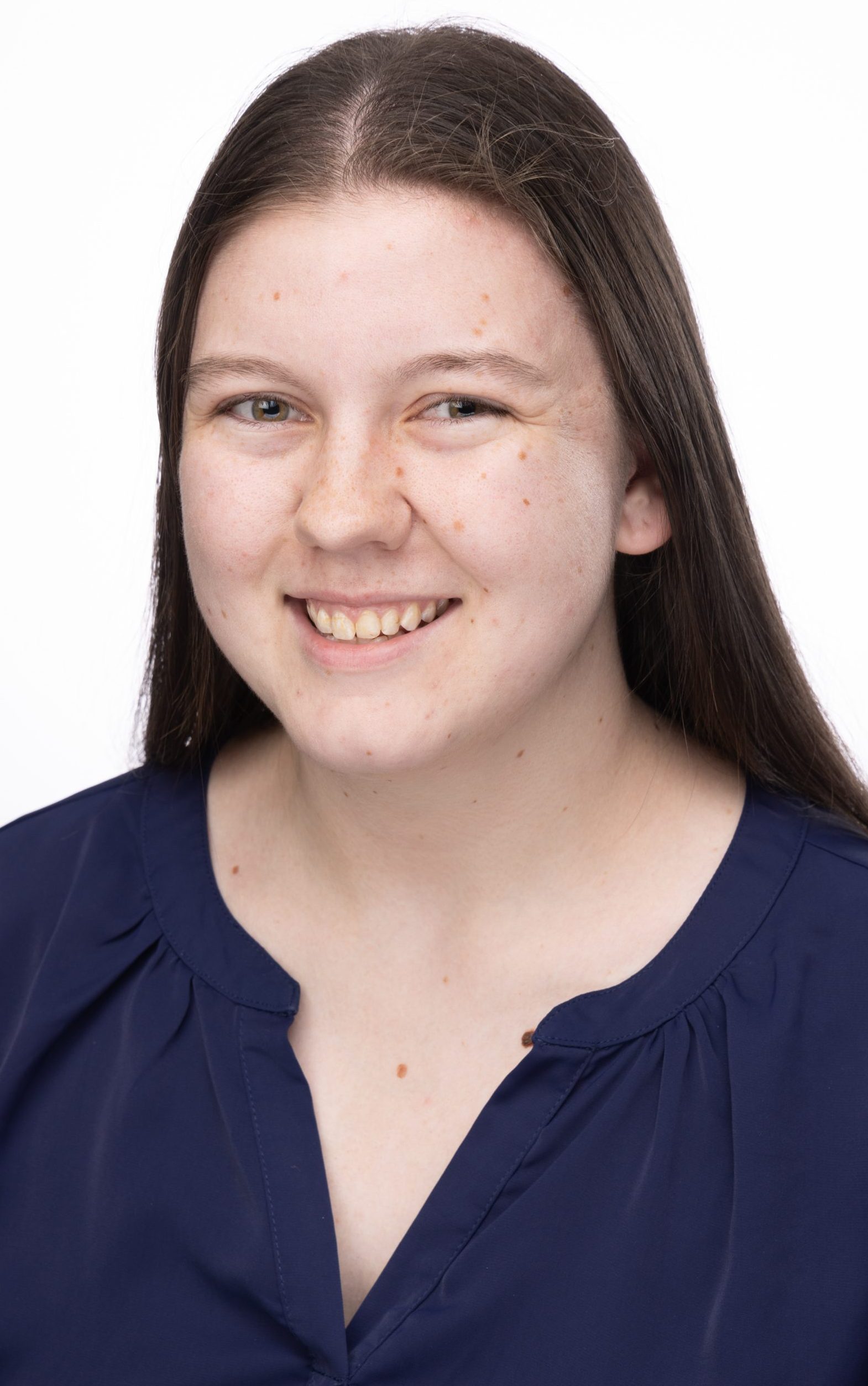 Headshot of a smiling woman with long dark brown hair wearing a navy blouse against a white background
