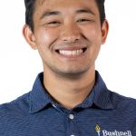 Headshot of a man with short dark hair, wearing a blue Bushnell polo shirt, smiling against a white background
