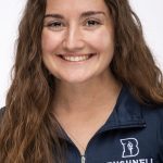 Headshot of a smiling woman with long brown hair wearing a navy Bushnell Athletic Training top against a white background