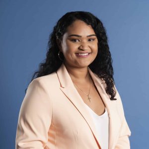 Female basketball coach poses for a professional headshot in front of a blue background