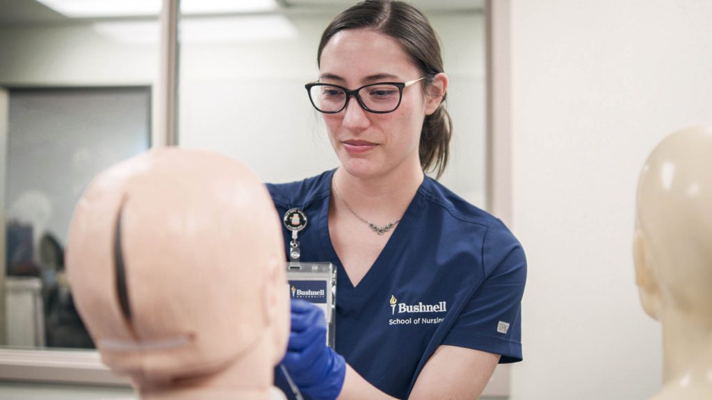 Bushnell University nursing student practices patient assessment during a clinical simulation lab.