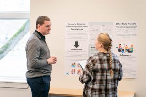 A Bushnell University student presents research findings during a poster session while discussing the project with a faculty member.