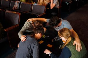 Four students huddled in a circle and praying