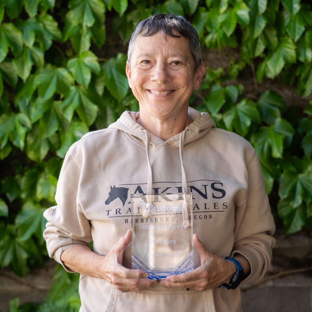 Employee recognized for 10 years of faithful service while holding a commemorative award outdoors on campus