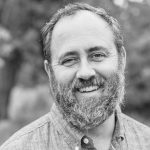 Black-and-white portrait of Craig Dickison smiling outdoors.