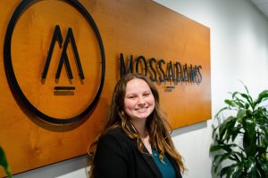 Student intern posing in front of the sign for a local accounting firm