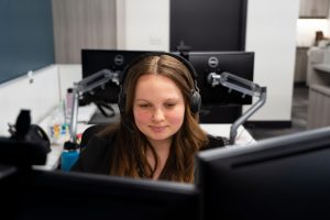 Student intern wearing a headset while working at computer monitors in an office environment
