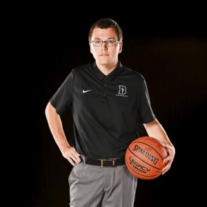 Young Bushnell basketball team manager dressed professionally with a basketball