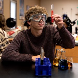 Student holding a test tube with liquid during a biology lab experiment