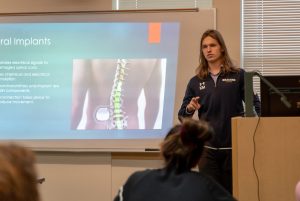 Male biology student giving a presentation during class with slideshow