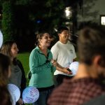 Bushnell University students gather outdoors in the evening, holding message-filled balloons and participating in a campus community event.