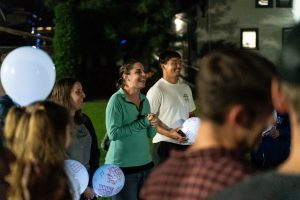 Bushnell University students gather outdoors in the evening, holding message-filled balloons and participating in a campus community event.