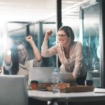 A business leader celebrates success alongside her colleagues in office