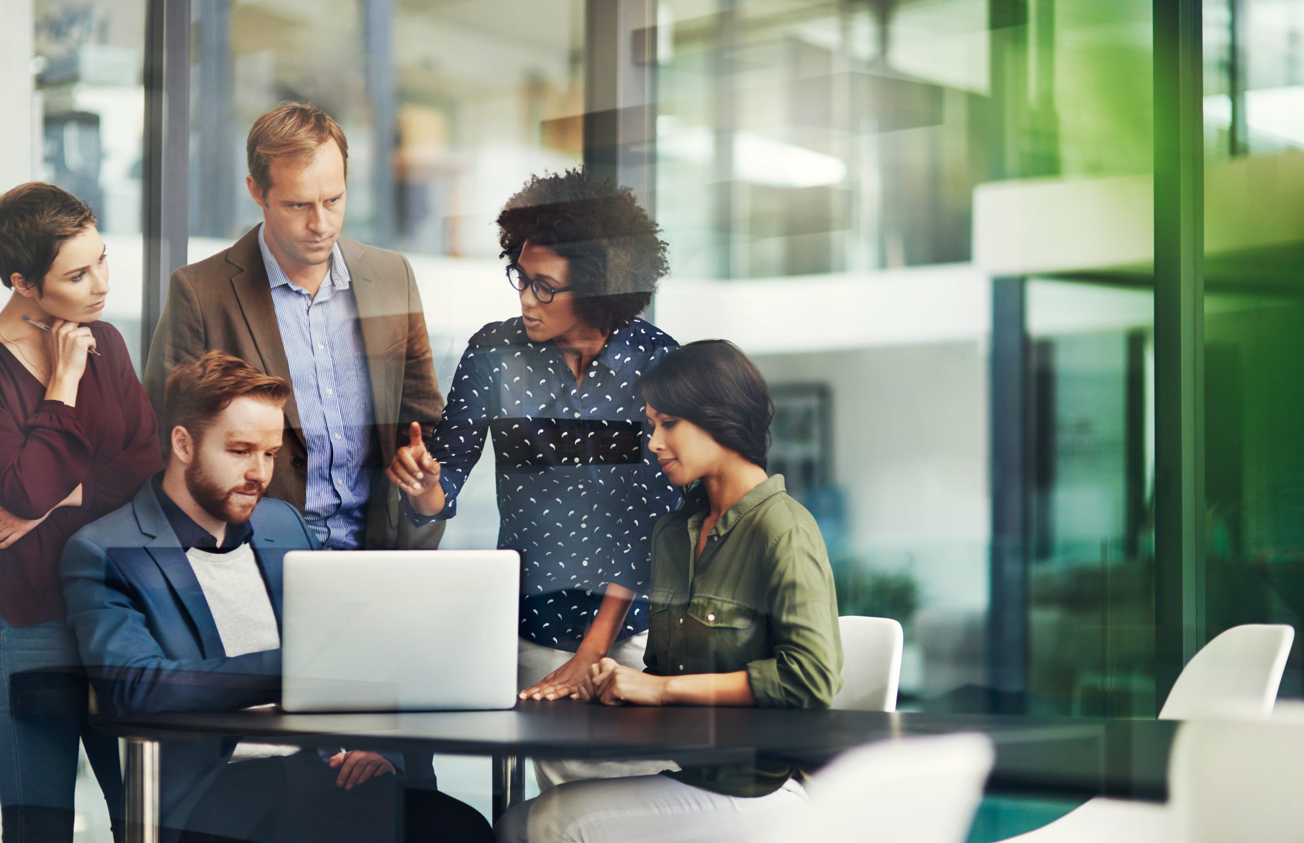 Colleagues in a group discuss a project in business office around computer