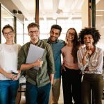 A group photo of a team of young professionals lauding and smiling together