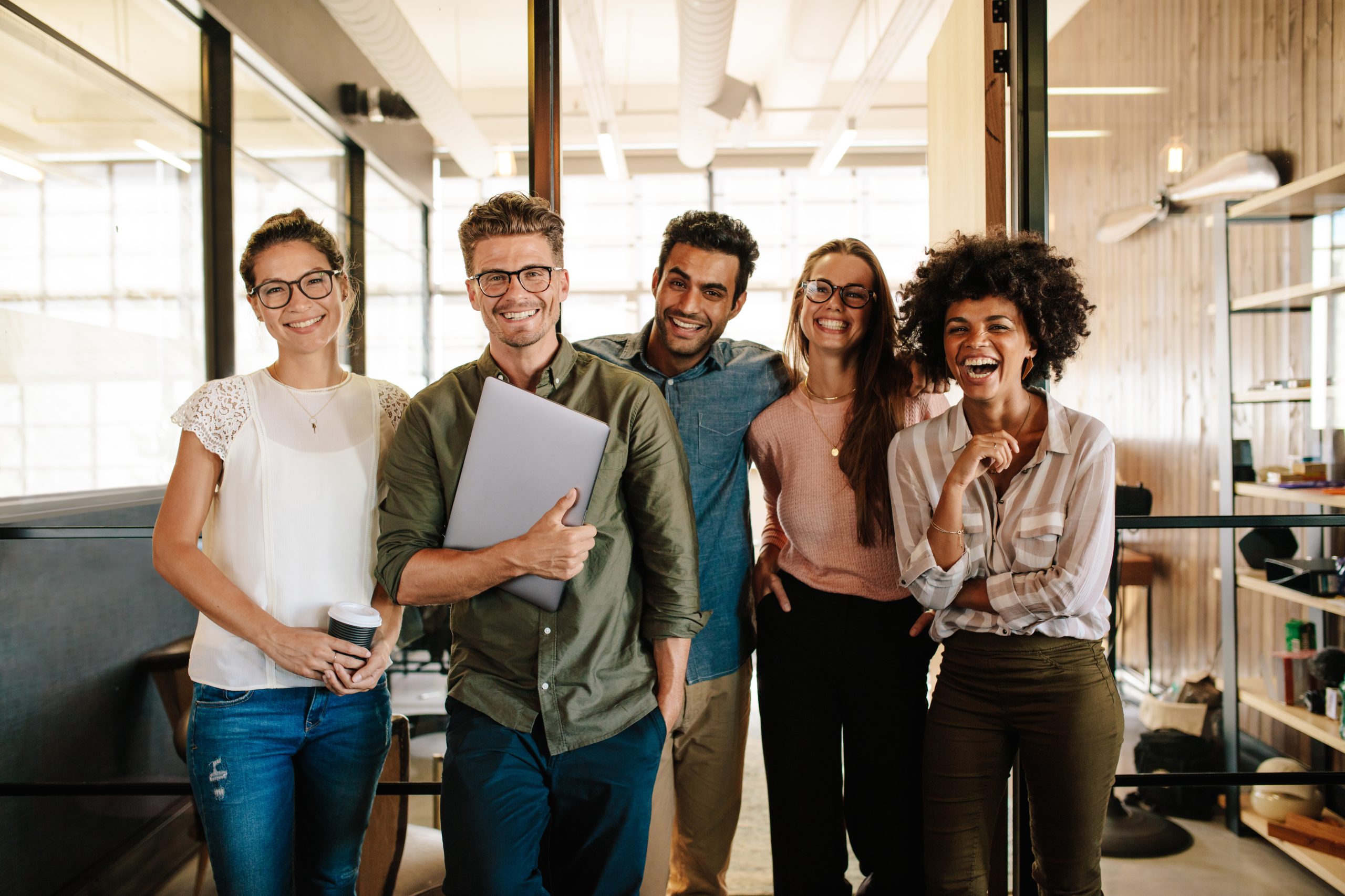 A group photo of a team of young professionals lauding and smiling together