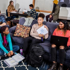 Student show off drawn design on paper to friends while in a study lounge