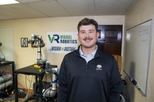 Computer science intern smiles in lab for robotics development internship