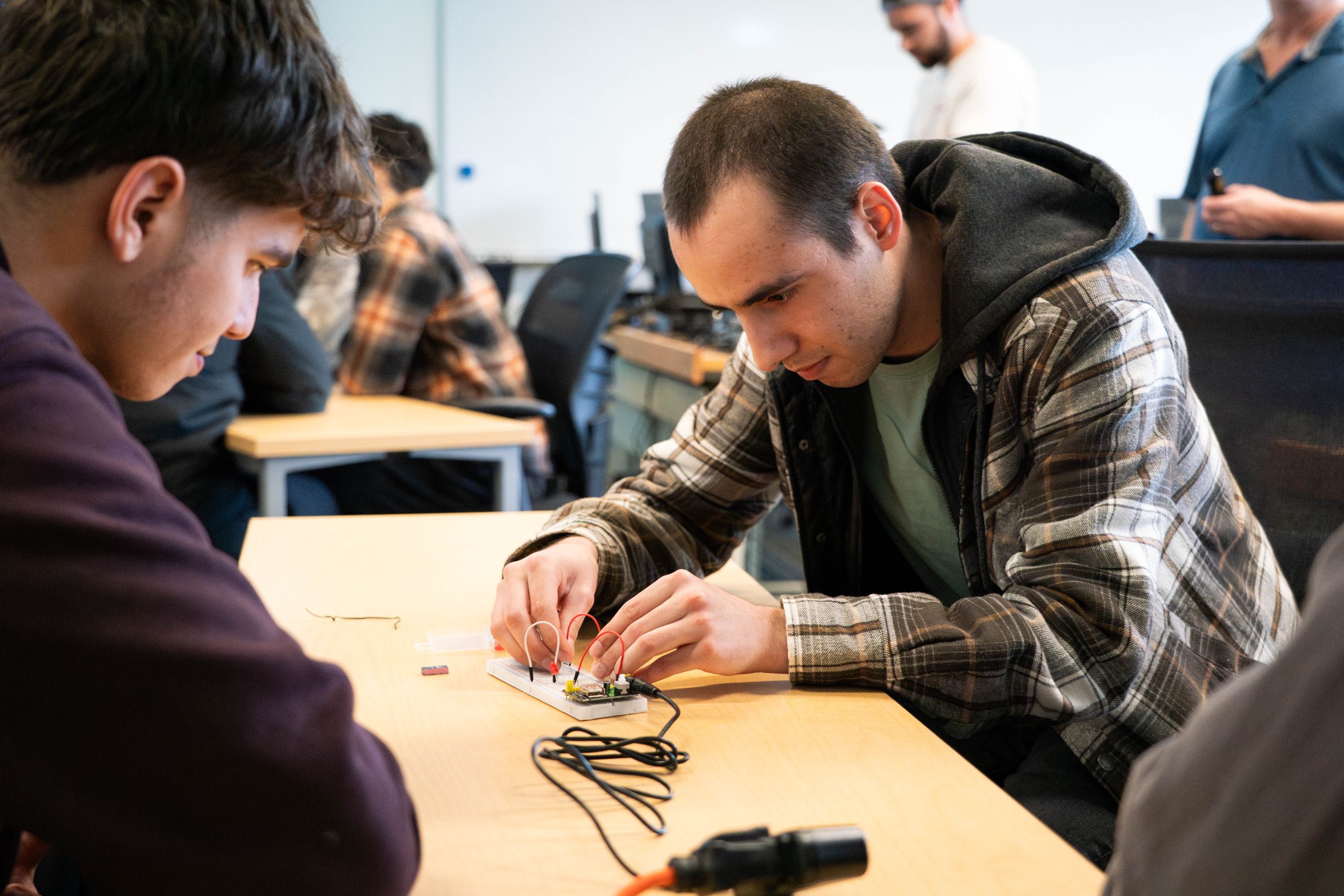 Computer science student wiring a practice circuit board in a classroom