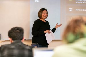 Female counseling professor presenting a slideshow at the front of a classroom