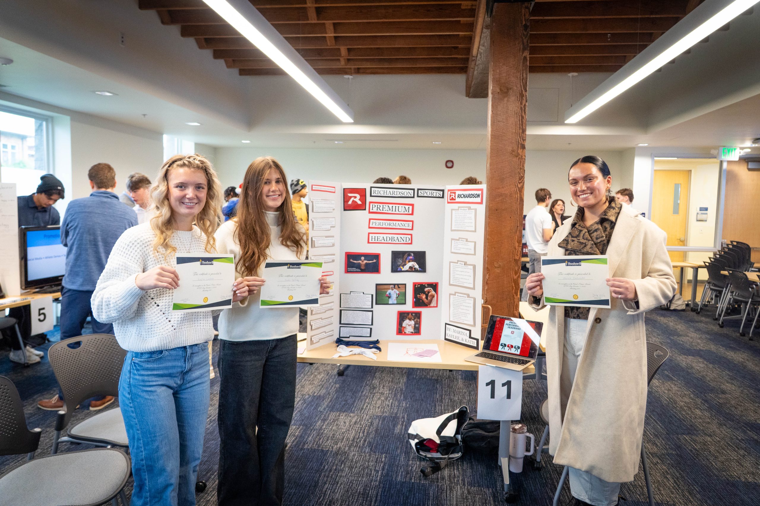 Digital marketing students holding awards beside their marketing pitch for a local business