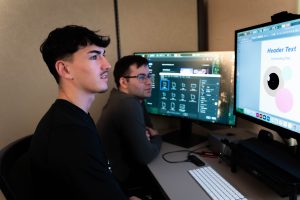 Marketing intern reviewing digital media layouts on computer monitors with supervisor