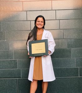 Female Bushnell alumna holding a Ph.D. certificate while wearing a lab coat