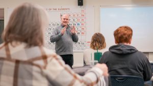 Male education professor giving a lecture at the front of class