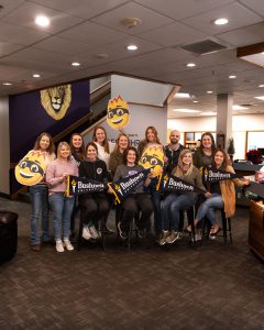 Educator alumni of Bushnell University pose together at Eugene Christian School with university gear