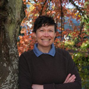 Female counseling student wearing a sweater with a fall tree background