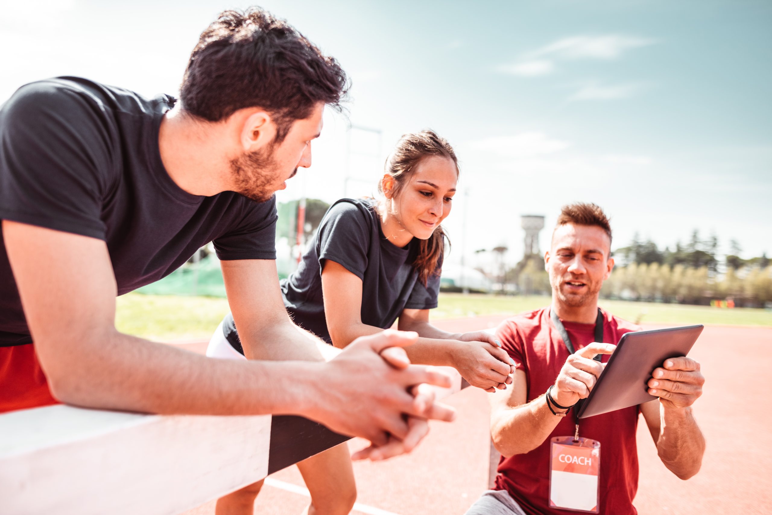 Athletes receive instruction from a fitness coach while on a track