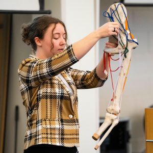 Student demonstrates a self-made model of a hip and knee joint using string and paper mache