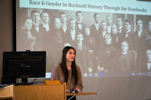 Student speaking during presentation featuring historical photo in slideshow