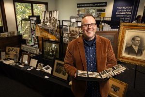 History professor presenting archival photographs and historical artifacts during a university history exhibit