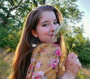Female honors student headshot smelling flowers in a forest