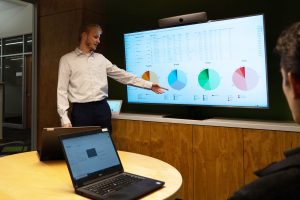Business intern points to graphs during a slideshow presentation