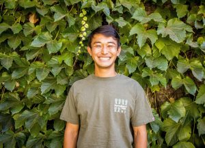Headshot of a male student against an ivy covered wall