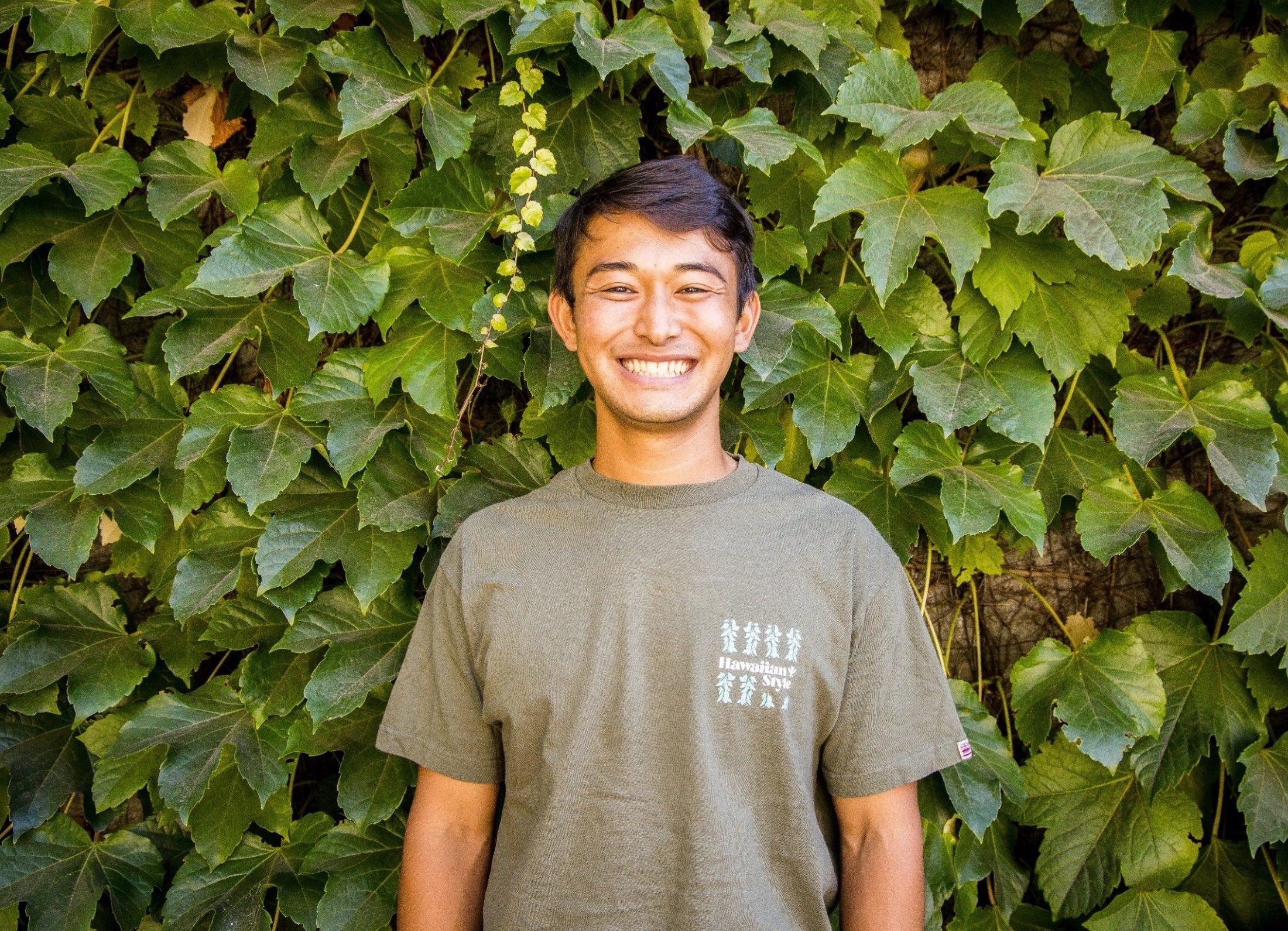 Headshot of a male student against an ivy covered wall