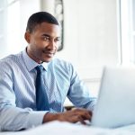 A young man in professional clothes focussing on a laptop