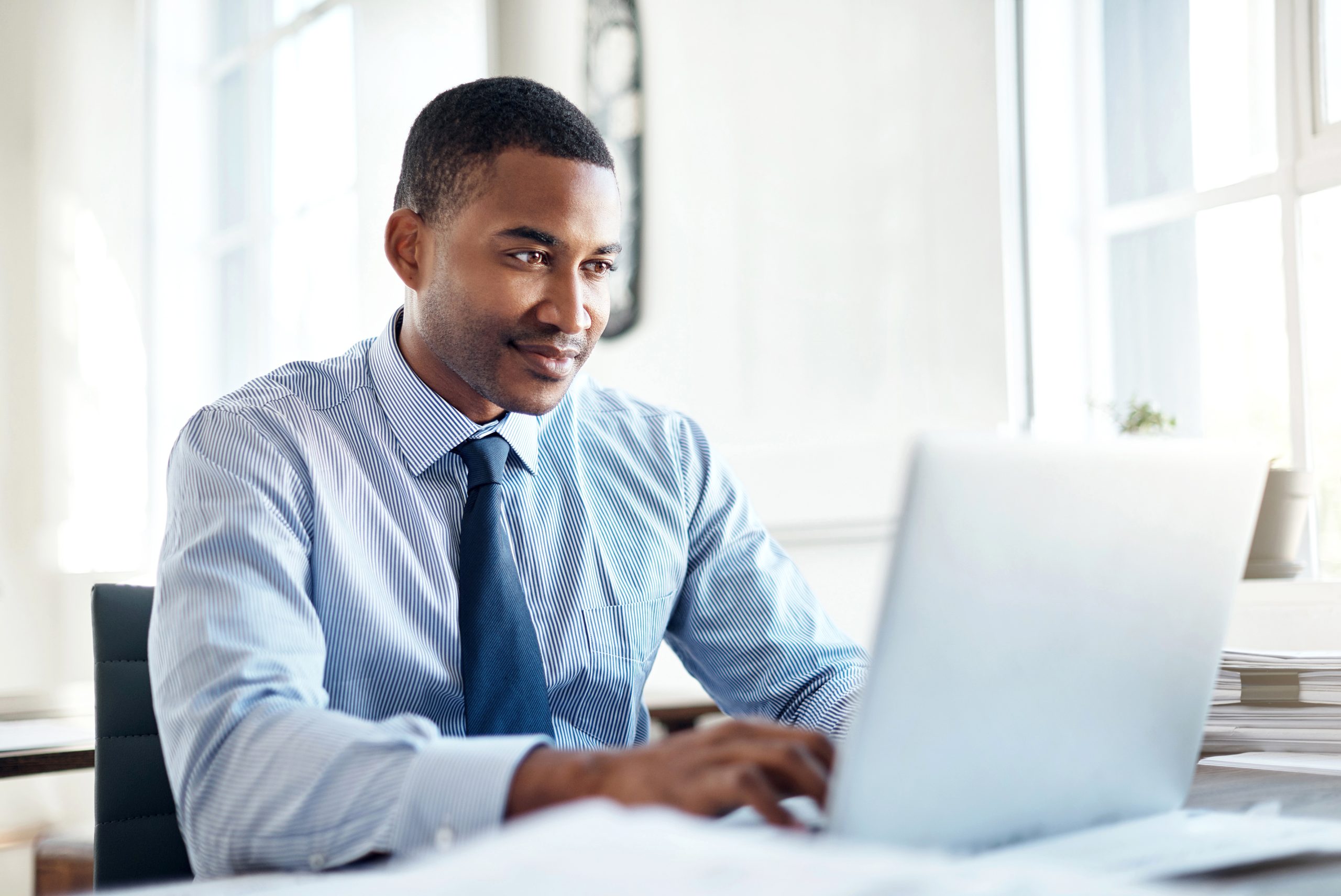 A young man in professional clothes focussing on a laptop