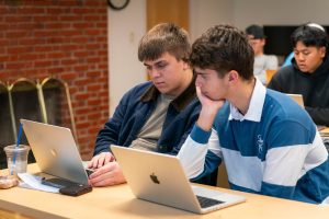 Digital marketing students work on computers together in classroom setting
