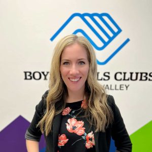 Nonprofit professional standing in front of Boys & Girls Clubs of Emerald Valley sign