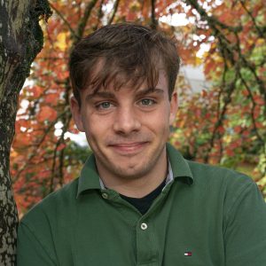 Male student headshot wearing a green shirt during the fall